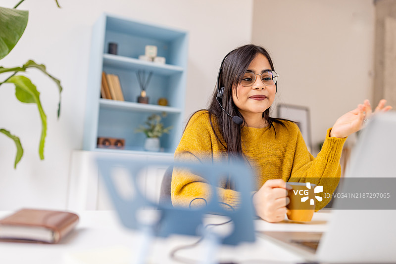 专注的女性在虚拟会议中喝咖啡图片素材