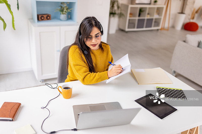 专注的女性在在线会议中写笔记图片素材