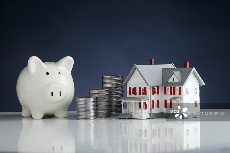 储蓄罐、模型房屋和一堆硬币 - 储蓄的概念图片素材