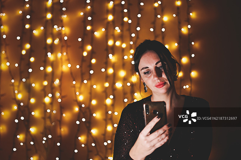 在派对上，化妆的伤心女人正在使用手机。图片素材