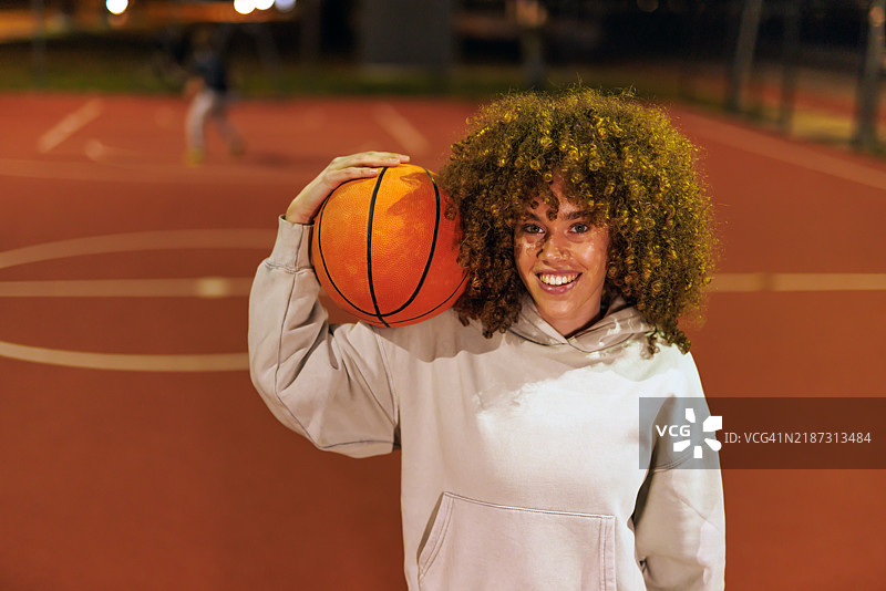 女人在城市夜晚的篮球场上快乐地摆姿势图片素材