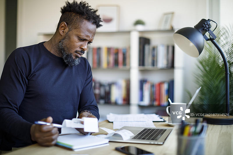 男子在家中审核收据以准备报税图片素材