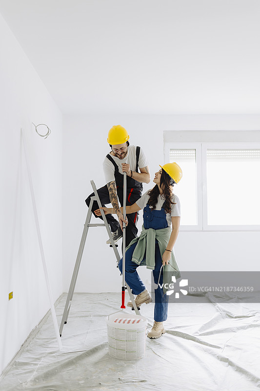 年轻工人在室内使用绘画工具进行房间装修。图片素材