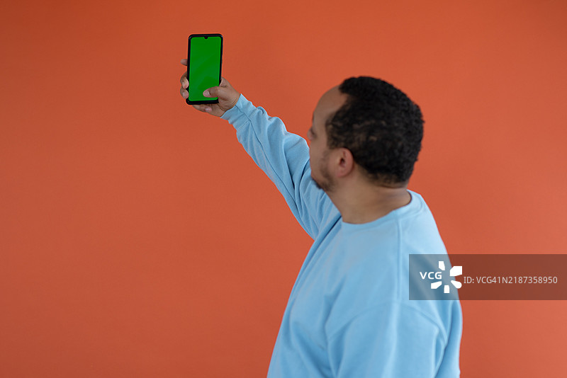 一位年轻的非裔美国男性在简单的背景前微笑自拍。图片素材