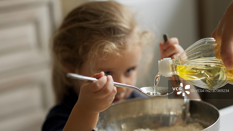 孩子在做面团，妈妈在倒油图片素材