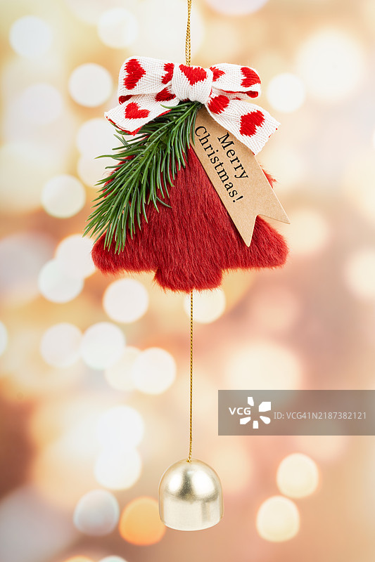 红色纺织品制成的圣诞树和模糊光点上的铃铛，圣诞装饰概念。图片素材