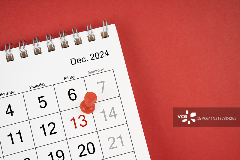 特写的2024年12月桌面日历，聚焦于13号星期五，背景为红色，推送粉色。图片素材