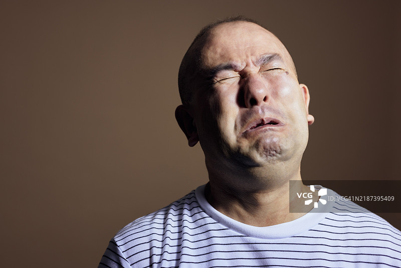 成熟男性在棕色背景的工作室中高高站立图片素材