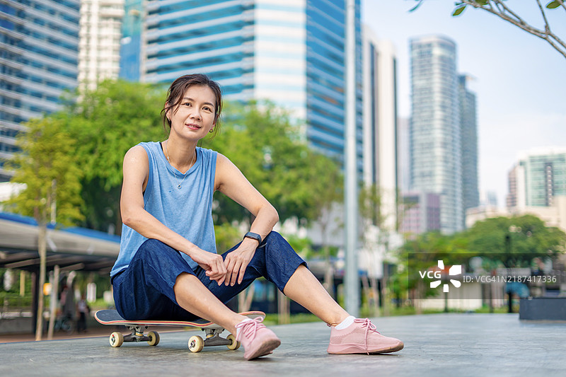 户外坐在滑板上的女性摆姿势拍照图片素材