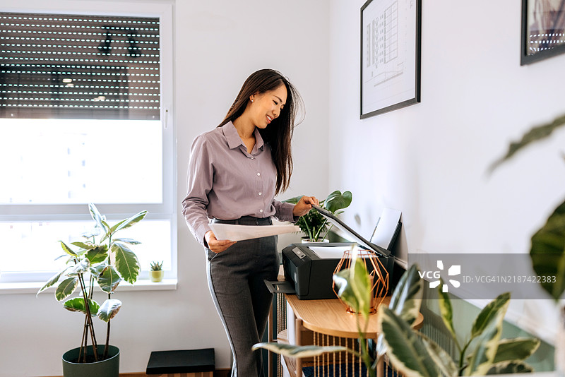 微笑的女商人在办公室使用打印机图片素材
