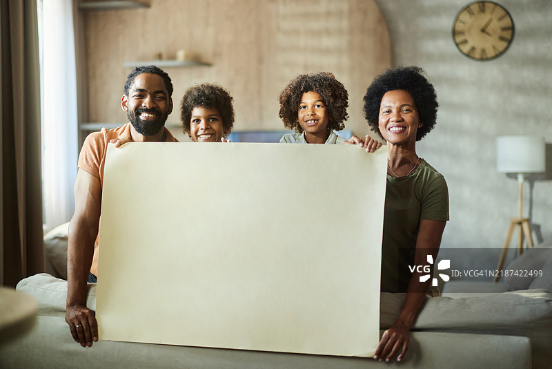 快乐的黑人家庭在家中举着空白标牌。图片素材