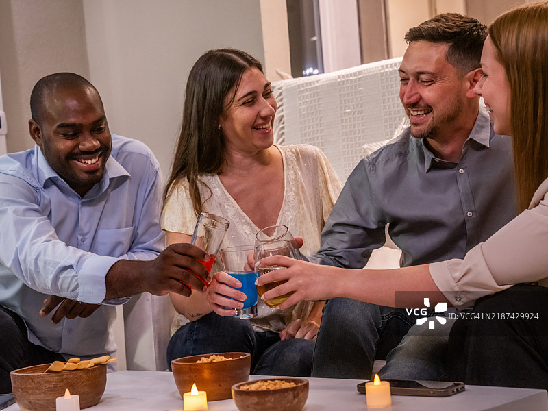 朋友们享受着温馨的庆祝活动，手中举着饮品，周围点着蜡烛。图片素材