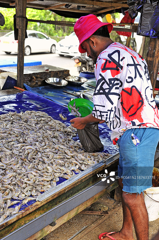 斯里兰卡加勒的市场上，鱼贩为顾客准备虾。图片素材