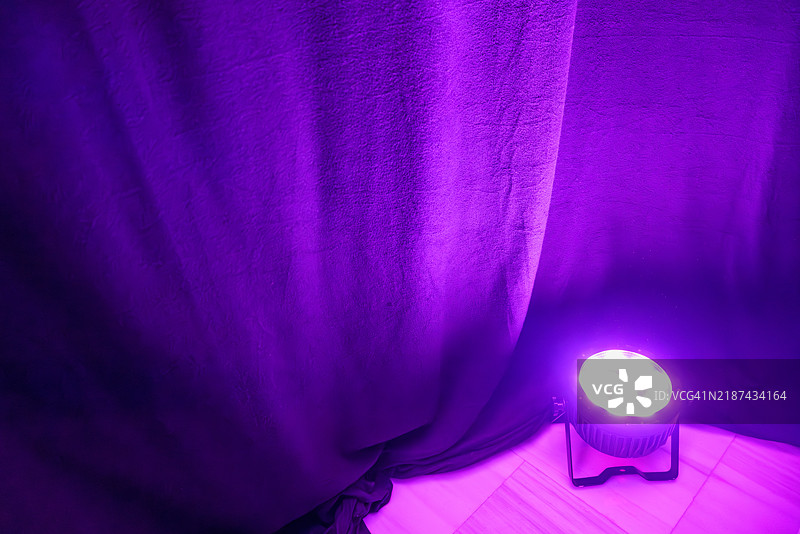 LED聚光灯照亮黑暗房间中的紫色窗帘图片素材