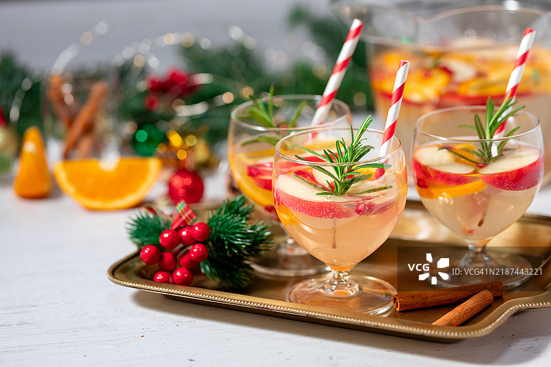 石榴圣诞红酒桑格利亚或果Punch饮品，搭配新鲜橙子、苹果和迷迭香枝，背景为圣诞装饰，留有空白空间。图片素材