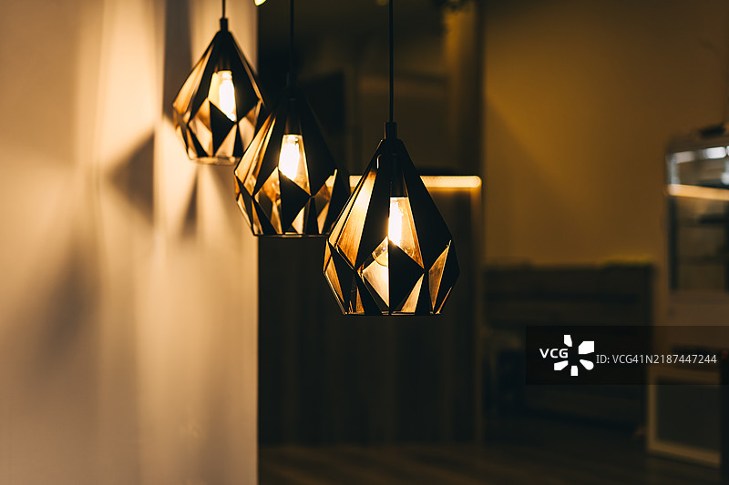 三个黑色现代吊灯作为房间设计，温暖的光线图片素材