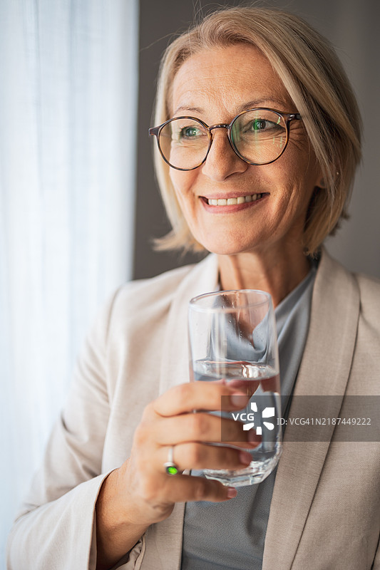 微笑的成熟的女性享受一杯清爽的水图片素材