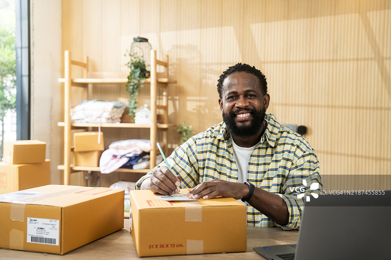 快乐的男人在家办公室准备发货包裹图片素材