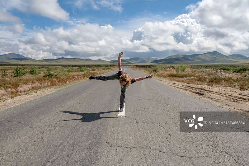 年轻女性在蒙古戈壁沙漠的公路上练习瑜伽姿势图片素材