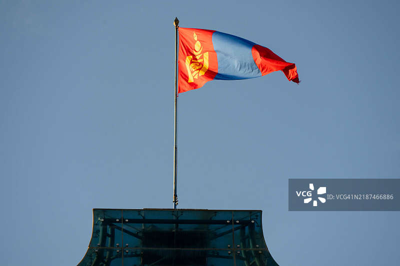 黄昏时分，蒙古国国旗飘扬在乌兰巴托市中心的国家大呼拉尔（议会大楼）顶部。图片素材