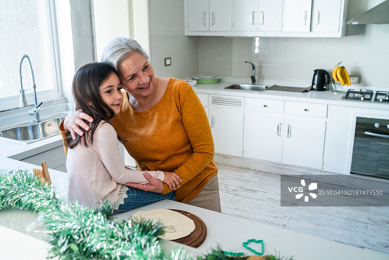 祖母和孙女在温馨的厨房中相拥图片素材