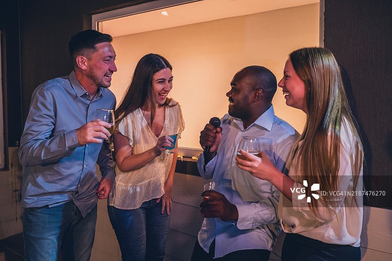 快乐的朋友们在卡拉OK之夜享受饮品和欢笑图片素材