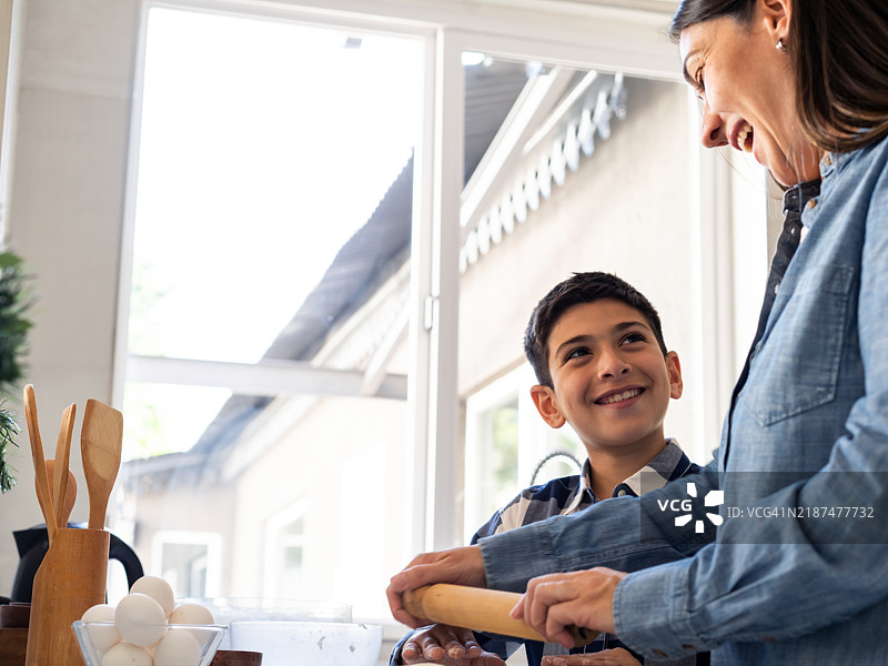 母亲和儿子在厨房一起烘焙时微笑图片素材