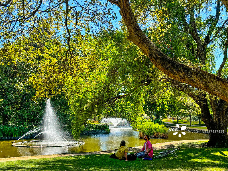 人们在墨尔本的卡尔顿花园里坐在地上放松。图片素材