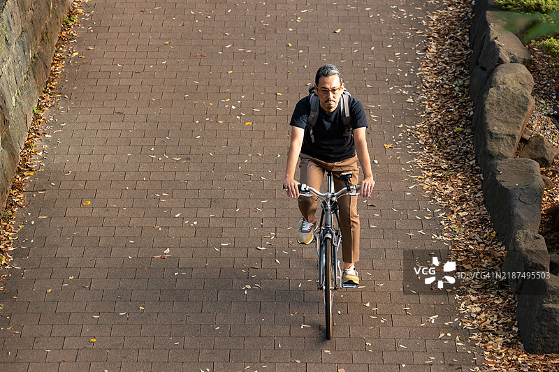 一位商人在城市中骑自行车出行工作。图片素材