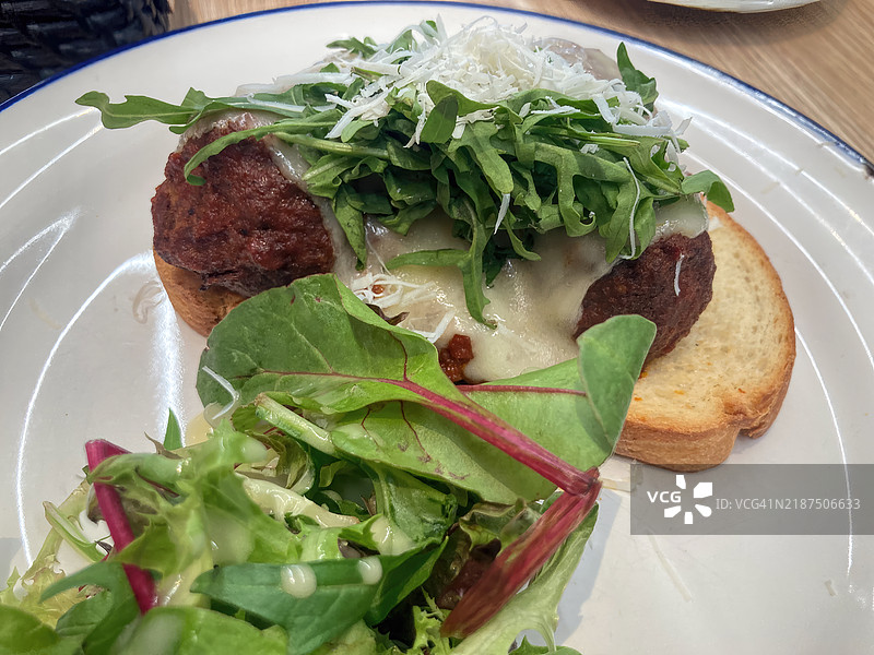 番茄酱牛肉和猪肉丸，配以普罗沃洛内奶酪和火箭菜，搭配酸面包吐司和一份绿叶沙拉图片素材