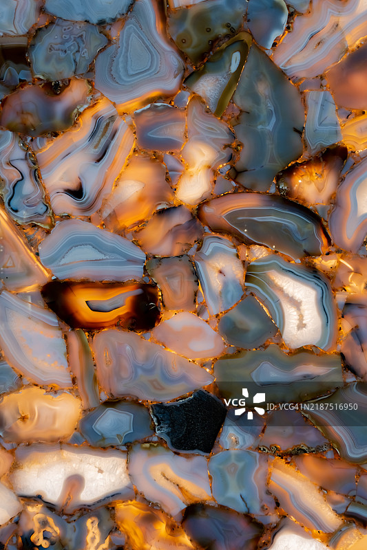 混合灰色、蓝色和琥珀色调的半透明玛瑙石的细节视图，形成抽象马赛克。优质自然设计表面概念。图片素材