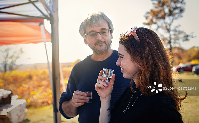 在吉姆·索普的节日聚会。家人在感恩节期间在秋天的树冠下分享饮品。图片素材