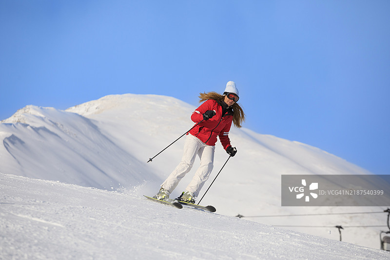 活跃的生活方式，充满活力的女性滑雪者在完美的滑雪坡道上高速滑雪，享受阳光明媚的塞拉隆达滑雪度假区。多洛米蒂超级滑雪区的雪山。意大利瓦尔加尔德纳滑雪度假村。图片素材