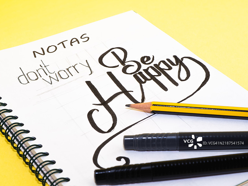 快乐点，不要担心：灵感名言与笔和铅笔的笔记本图片素材