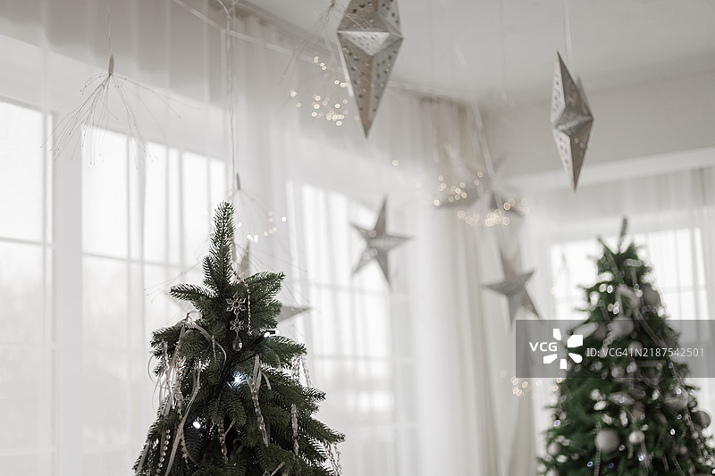 白色房间里的新年树和悬挂的星星。图片素材