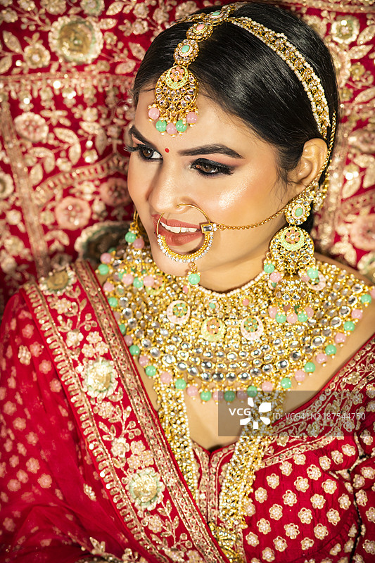 美丽惊艳的印度新娘，身穿传统的红色婚纱，佩戴着华丽的珠宝。图片素材