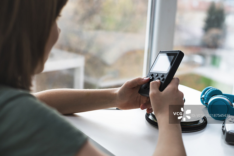 孩子在便携式复古电子游戏机上玩耍图片素材