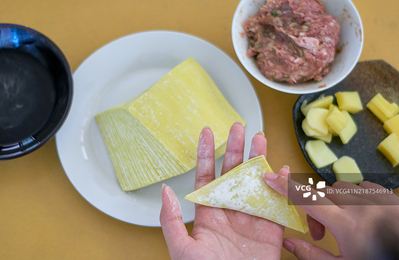 女性将调味猪肉末和奶酪包裹在饺子皮中图片素材
