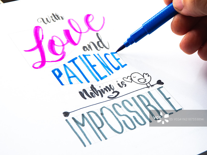 艺术家用蓝色马克笔耐心地绘制字母。图片素材