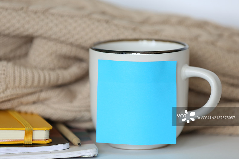 白色陶瓷茶杯上的蓝色粘性贴纸，背景为学生用品图片素材