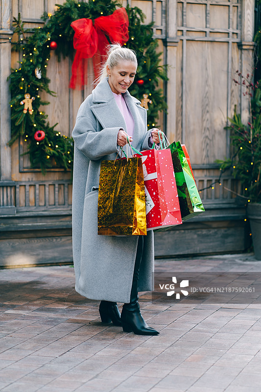 女人在圣诞市场上手持圣诞礼物和购物袋图片素材