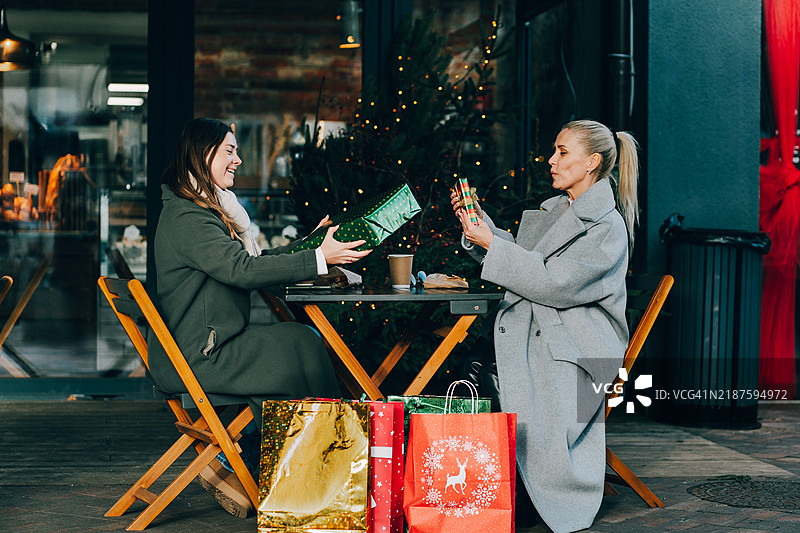 女性在户外咖啡馆里互换圣诞礼物图片素材
