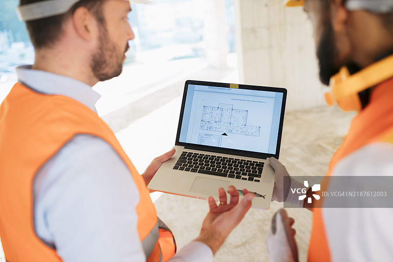 工程师和建筑师在工地上讨论笔记本电脑上的建筑计划图片素材