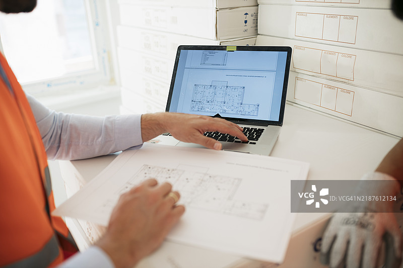 建筑工人和建筑师在工地上一起查看笔记本电脑上的计划图片素材