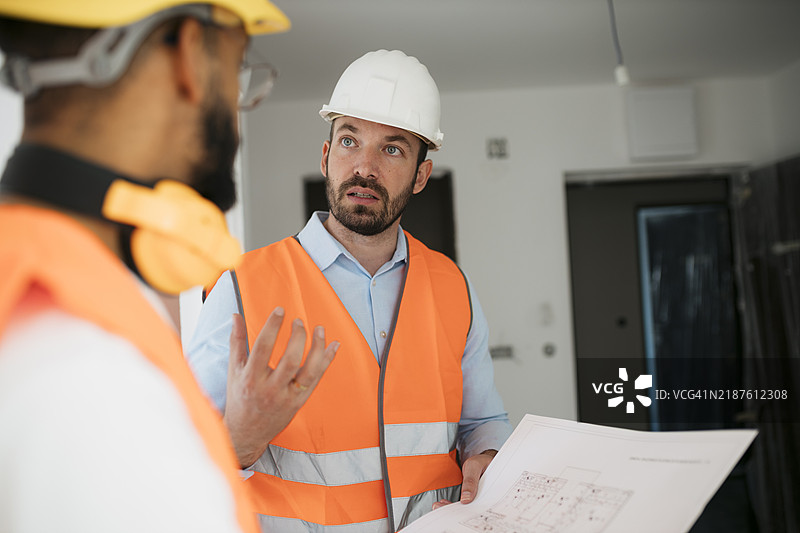 建筑师和工人在现场审查建筑计划图片素材