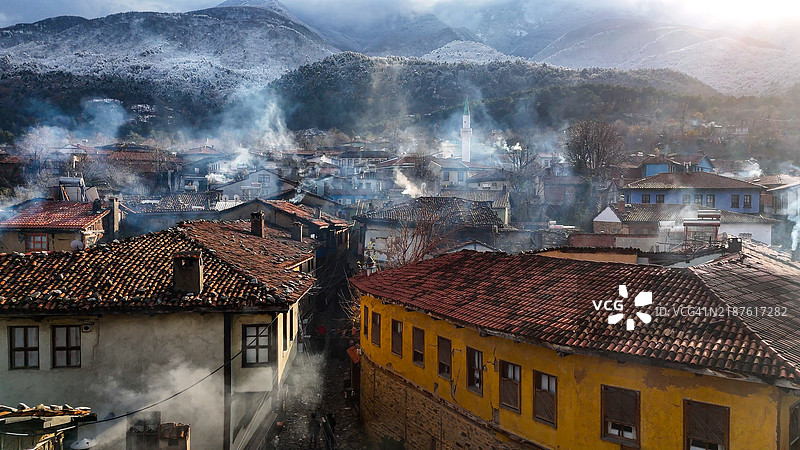 迷人的空中视角，展示土耳其布尔萨的库马利基兹克村，四周环绕着白雪皑皑的山脉和传统的奥斯曼建筑，库马利基兹克村的永恒之美，保留着奥斯曼遗产和真实的建筑风格。图片素材