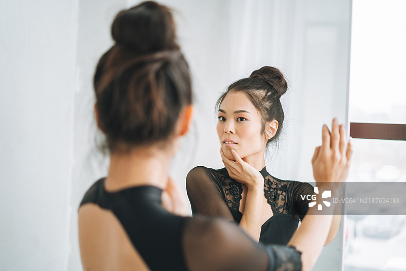 年轻美丽的日本芭蕾舞者穿着芭蕾裙在舞蹈室的镜子前图片素材