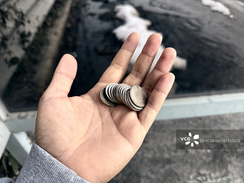 一只手在户外握着一叠硬币图片素材