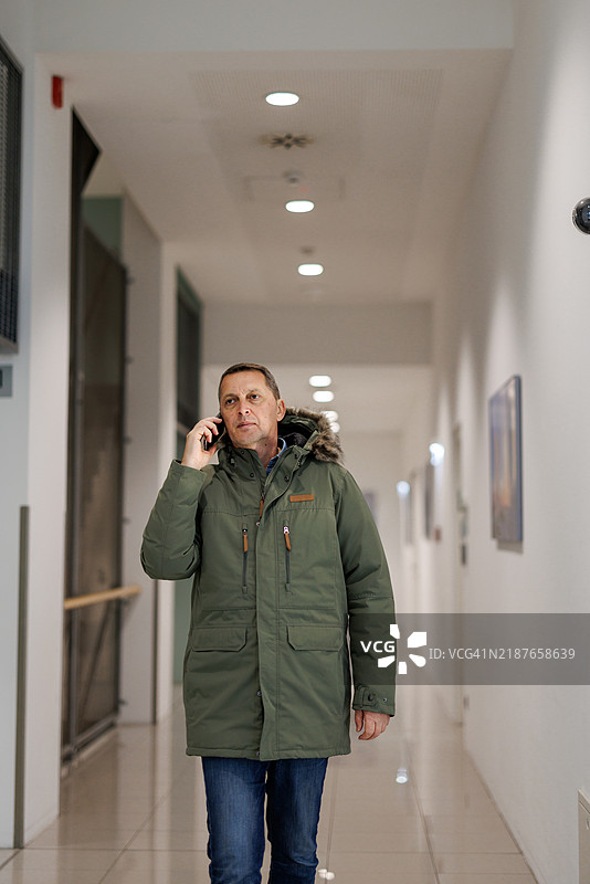 在建筑走廊里打电话的男人图片素材
