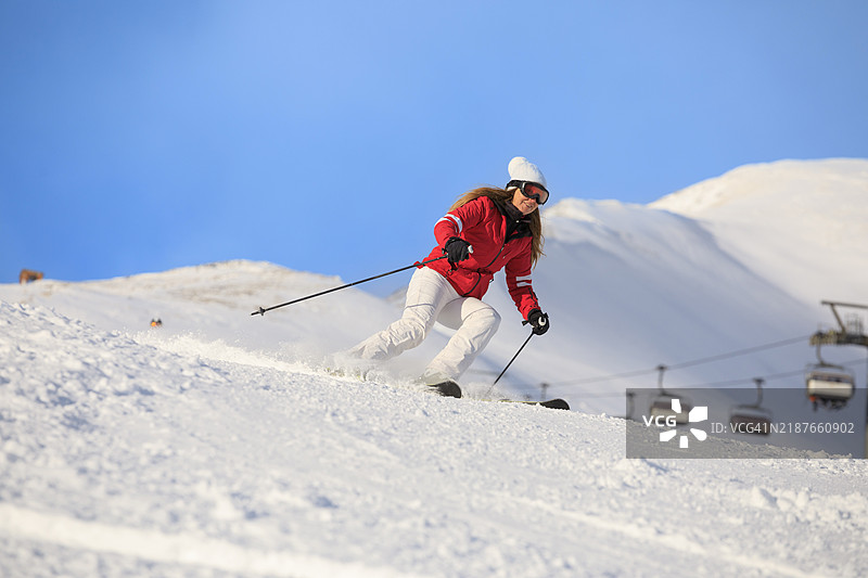 冬季运动，女性滑雪者在完美的滑雪坡道上高速滑雪，享受阳光明媚的塞拉隆达滑雪度假区。多洛米蒂超级滑雪区的雪山。意大利瓦尔加尔德纳滑雪度假村。图片素材